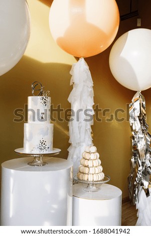 decoration for first birthday with two story cake and big white and beige balloons with tinsel. Candy bar with macaroon or macarons. birthday party. selective focus