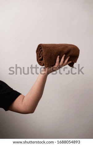 Brown bath towel in a woman's hand, on a white background, body and health care