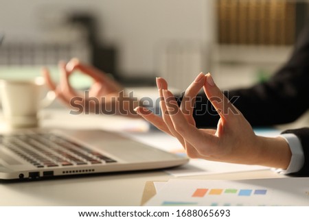 Close up of executive hands stress relieving doing yoga pose at night sitting on a desk in the office Royalty-Free Stock Photo #1688065693