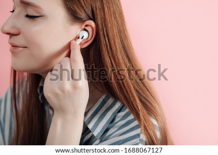 girl uses wireless white headphones on a pink background. Air Pods Pro. EarPods New Airpods pro on pink background. Airpodspro. female headphones.EarPods Royalty-Free Stock Photo #1688067127