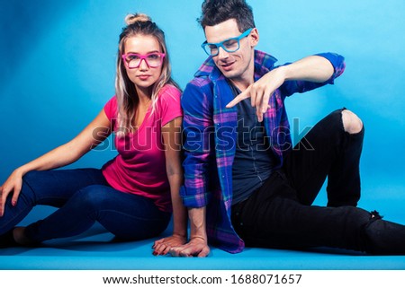 happy couple together posing cheerful on blue background wearing glasses, guy and girl students together friends
