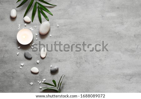 Spa concept on stone background, palm leaves, candle and zen, grey stones, top view, copy space