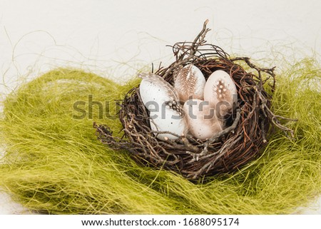 Pastel Easter eggs in bird's nest on a green grass
