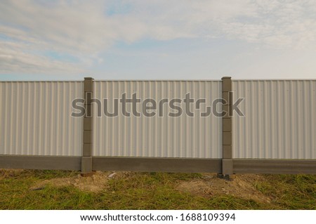 Metal painted fence on concrete poles by the countryside