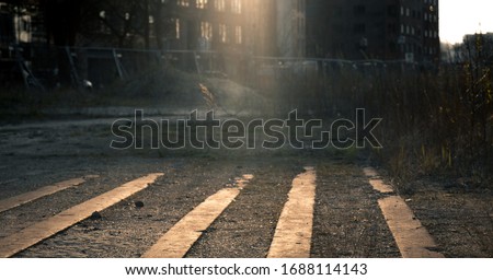 Low angle view of a deserted city street at night lit by beams of light from illuminated apartment windows with rows of paving in gravel in the foreground in an atmospheric urban landscape Royalty-Free Stock Photo #1688114143