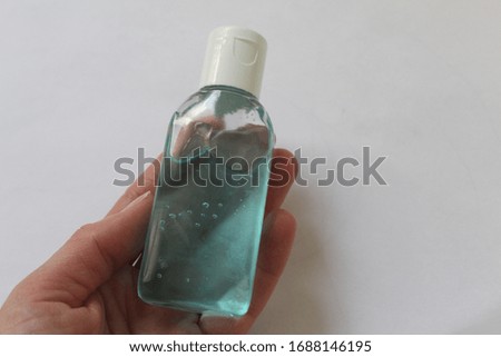 Plastic bottle of antiseptic hand gel on hand with white background.