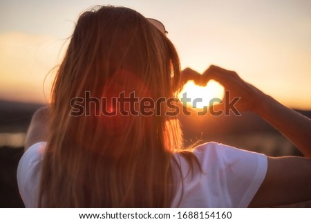 Love sign. Woman making heart with her hands at sunset.