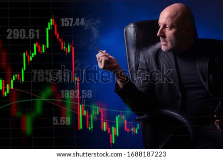 A man smokes in a chair and looks at the data of stock trading. Stock quotes. Charts of changes in quotations on the exchange. Japanese candlestick. Work on the stock market. Forex.