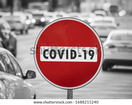 Road sign 'No entry Covid-19' on the background of passing cars traffic. Coronavirus control concept. Selected Focus
