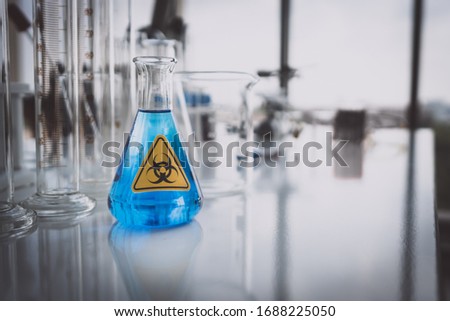 Blue Testing Chemical in  Chemical Glassware with Yellow Biohazzard sign in Lab