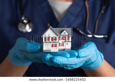 Female Doctor or Nurse Wearing Surgical Gloves Holding Model Home. Royalty-Free Stock Photo #1688225602