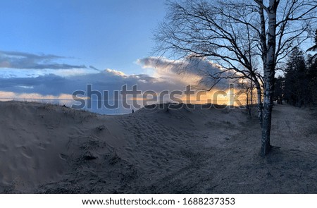 The coast at sunset, the picturesque sunset, quiet water, a sandy beach, clouds are illuminated by the sunset sun, Specular reflection in water