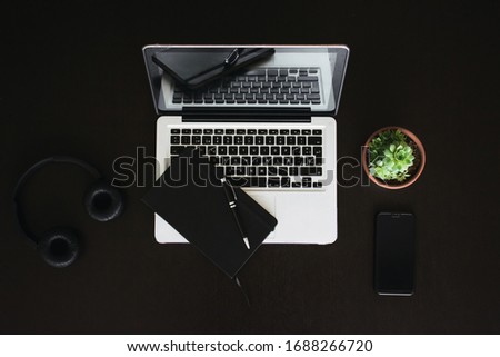 Minimalist desk top view. Everyday gadgets. Laptop, cactus, headphones, notebook, smartphone, pen.