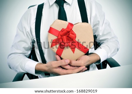man wearing a suit sitting in a table with a heart-shaped gift in his hands