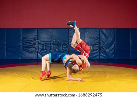 Two men in sports wrestling tights and wrestling during a traditional Greco-Roman wrestling in fight on a wrestling mat. Wrestler throws his opponent’s chest through