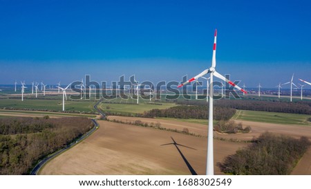 Zeestow, Brandenburg/Germany - 26.03,2020: A wind farm in Brandenburg with many wind turbines scattered across the landscape in sunshine on fields and meadows.