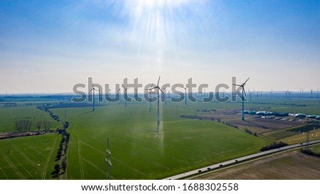 Zeestow, Brandenburg/Germany - 26.03,2020: A wind farm spread over the landscape up to the Horizent in sunshine with a road in the foreground.