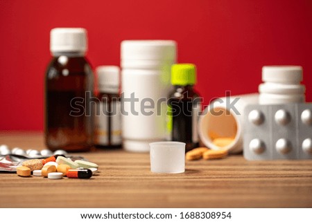 Closeup view photography of many different colorful pills laying on brown wooden surface of table.