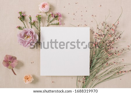 Empty white paper blank, flowers, branches on beige background. Wedding branding mock up,  holiday marketing concept.