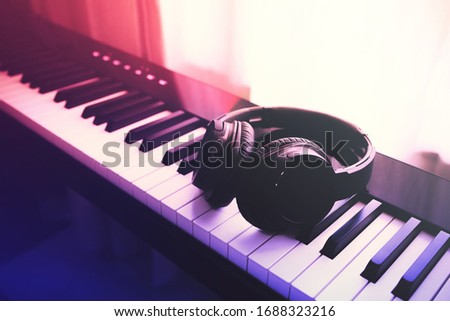 Music headphone on piano keyboard with sunlight through the window. Vintage filter.