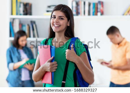 Successful hispanic female student with group of young adults at classroom of university
