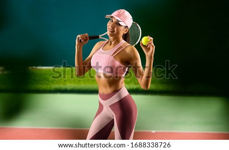 Beautiful female tennis player on court background. 