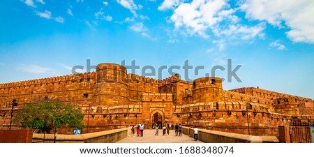 Agra Fort - Historic red sandstone fort of medieval India on bright sunny day. Agra Fort is a UNESCO World Heritage site in the city of Uttar Pradesh India. Tourists at entrance to Agra Fort. - Image Royalty-Free Stock Photo #1688348074