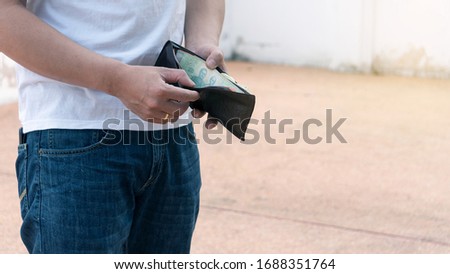 A man looking at his wallet, only a few baht during a break