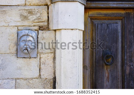 An ancient decoration set between the stones of a wall and a door of an old house.