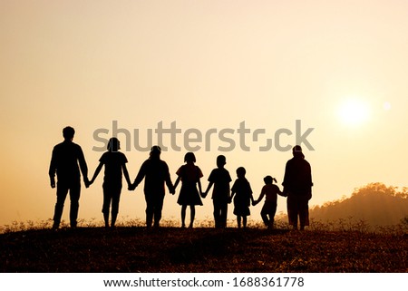 Silhouette of happy family standing on the mountain at the sunset time.