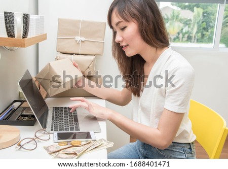Asian woman, the owner of an online sales business, holds a box to prepare to deliver to the customer according to the order at home.Work from home and marketing online concept.