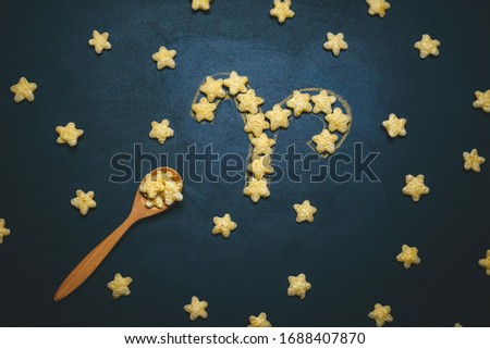 top view flat lay Taurus horoscope sign made from crispy corn stars on a black background 