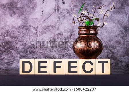 Word DEFECT made with wood building blocks on a gray back ground