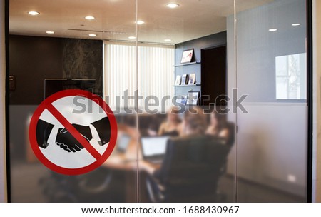 No handshake concept, changing greetings habits, sign at the entrance of a meeting room with employees having a meeting in a company