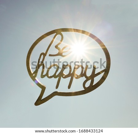 be happy (dont worry)-  wooden inscription isolated on blue sunny sky background. decoration for weddings. sun rays light. 