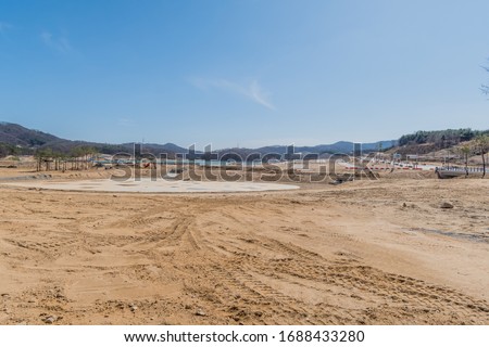 Landscape of construction site under clear blue sky with mountains in background.