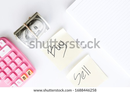 A flat lay picture of trading concept with calculator, fake money, note book, buy and sell paper on the table.