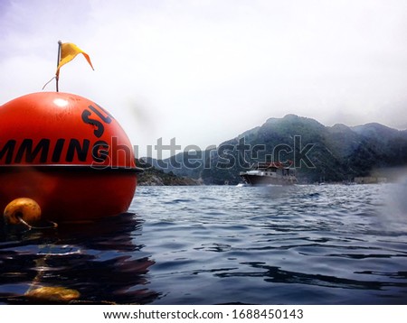 Sea surface with buoys with words No swimming and mountains in the distance. View and shooting from water in a summer day