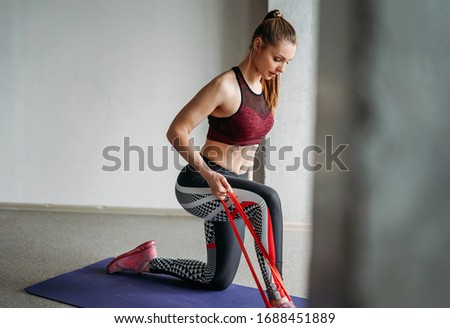 Attractive fit young woman sport wear fitness girl model doing stretching with elastic band at loft studio workout class