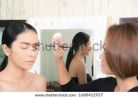 Young beautiful asian woman applying makeup by makeup artist on location.