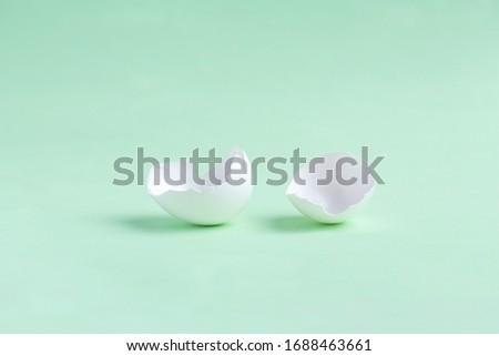 Broken egg on a light green background. monochrome. Minimal easter holiday concept