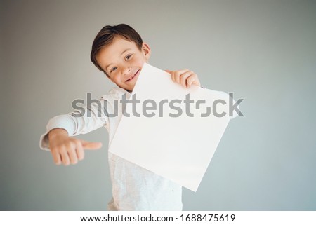 cool young boy holding white sign in front of grey background during corona crisis