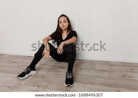 Portrait of an Asian girl in casual wear on a white background. black t-shirt and black jeans