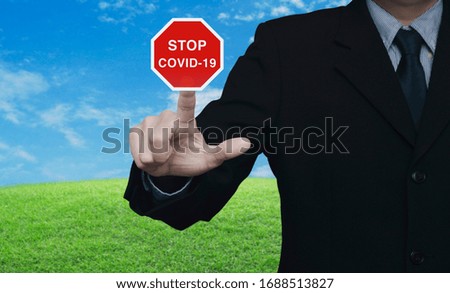 Businessman pressing stop COVID-19 outbreak flat icon plate over green grass field with blue sky, Global epidemic alert, Concept of novel coronavirus outbreak