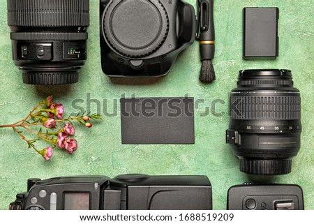 Modern photographer's equipment with card on color background