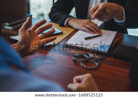 Law enforcement officer interrogating Criminals male with handcuffs in the investigation room Police officer interviewing after committed a crime Royalty-Free Stock Photo #1688525125