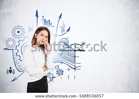 Pensive young businesswoman or college student in smart casual clothes standing near concrete wall with business plan sketch drawn on it. Concept of business education and strategy. Mock up