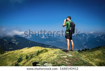 Sport tourist man hold in hands take photography click on modern photo camera, photographer look on camera technology, journey landscape vacation concept, sun flare mountain. Alps, Tyrol,  Austria 