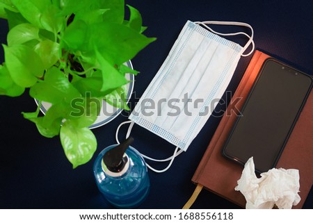 Top view, picture of hand sanitizer with medical surgical mask with green decorative tree Used tissue paper Mobile phones and notebooks. Control and prevent the spread of the corona virus on the desk Royalty-Free Stock Photo #1688556118