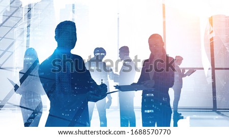 Concept of communication and business partnership. Silhouettes of diverse business people in panoramic office with double exposure of abstract cityscape.Toned image